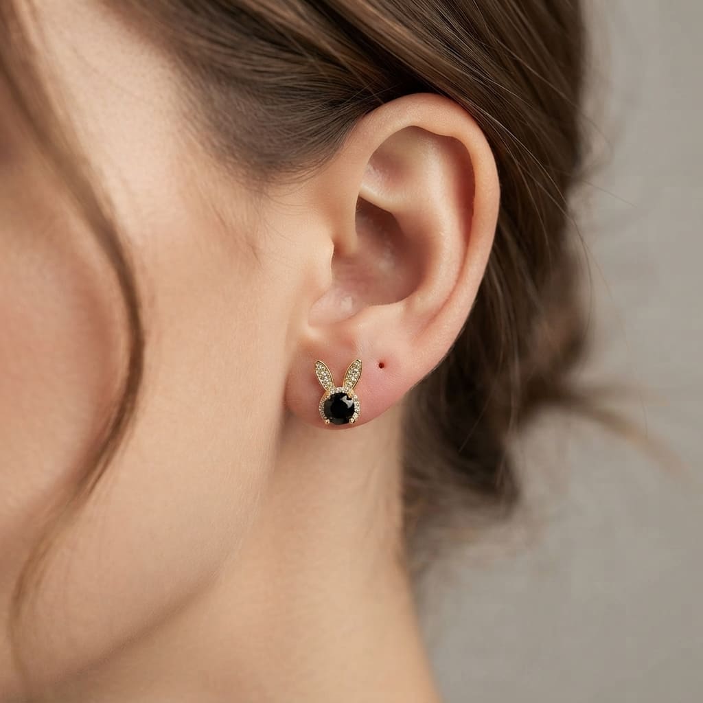 A pair of gold bunny stud earrings with black oval center stones wear by a women- Women Jewelry Pakistan