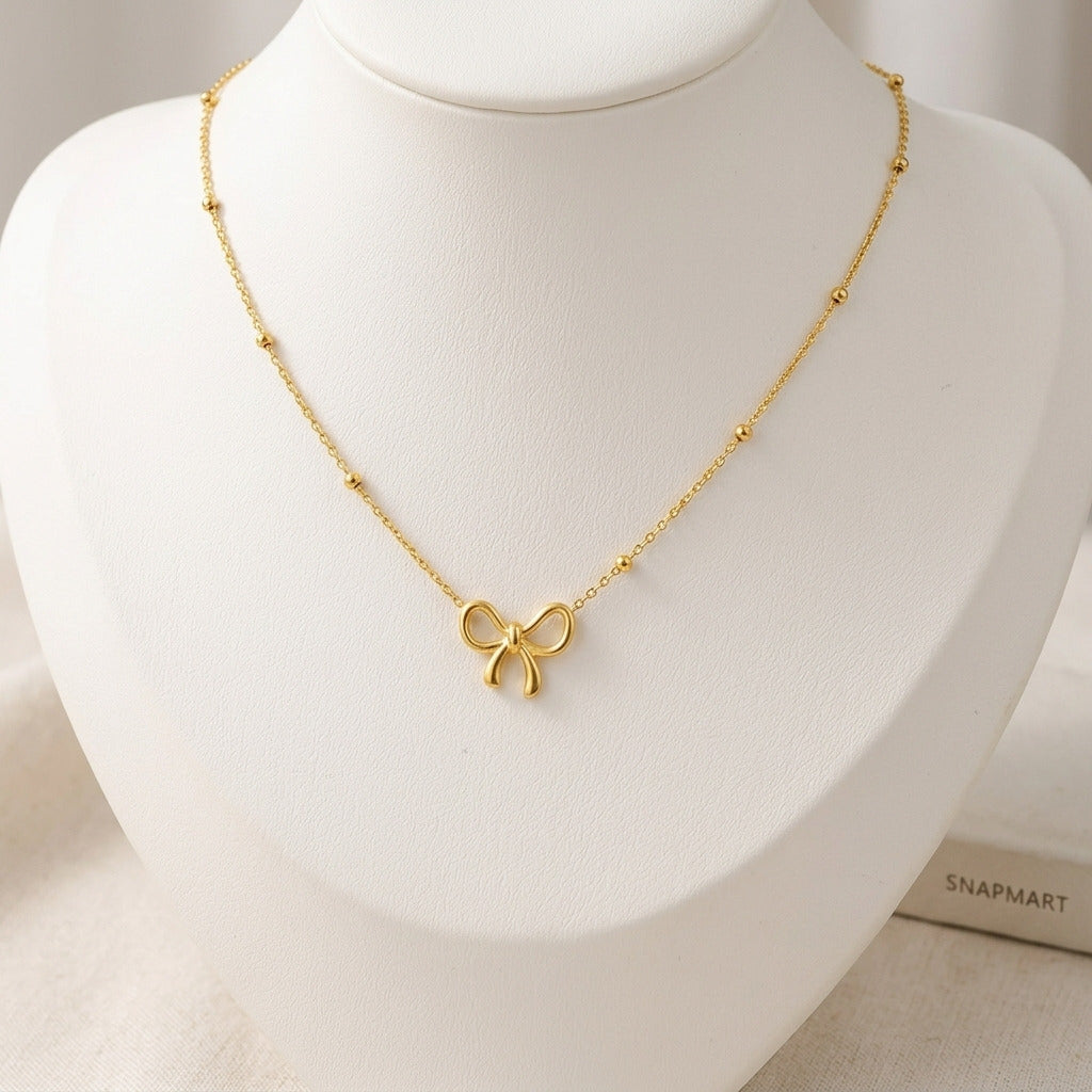 Dainty gold bow knot charm bracelet worn on wrist next to a Snap Mart brand tag - Snap Mart Pakistan