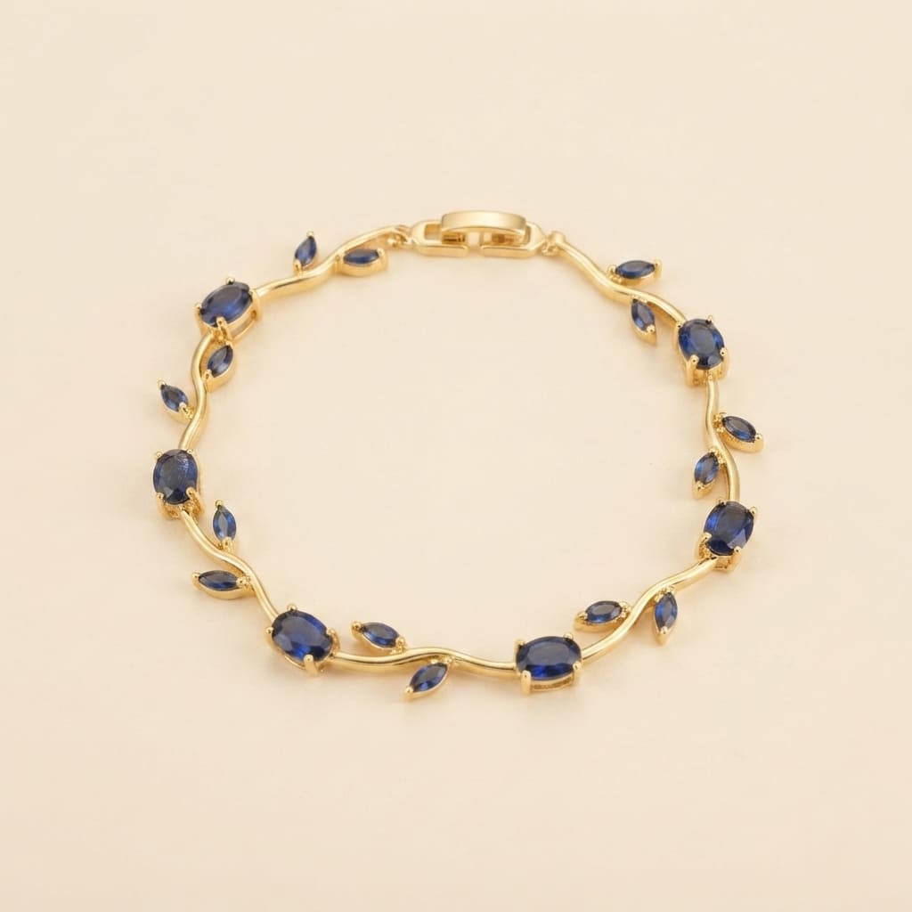 Gold vine-style tulip leaf bracelet with oval and marquise deep blue crystals on light beige background - Snap Mart Pakistan