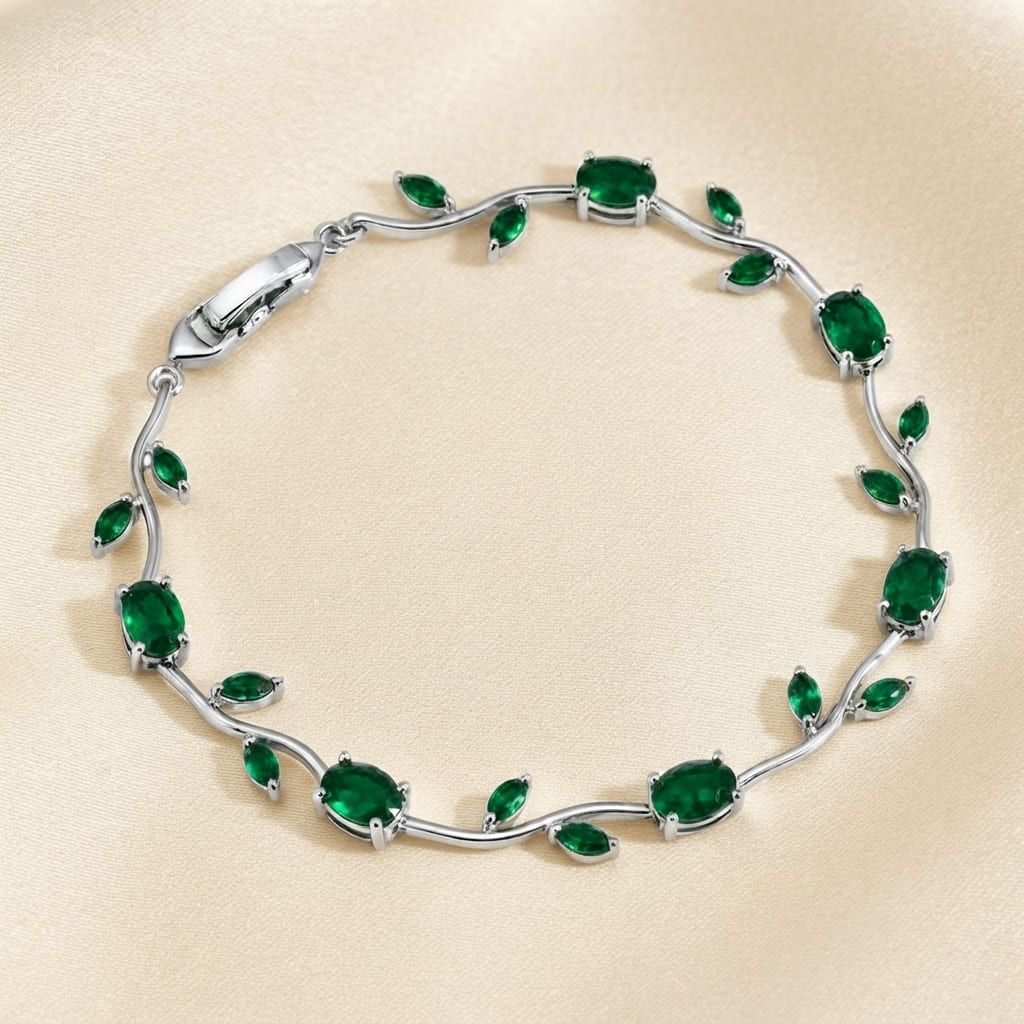 Silver vine-style tulip leaf bracelet with oval and marquise emerald green crystals on textured beige fabric - Snap Mart Pakistan