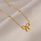 Close-up of gold bow knot charm bracelet with polished chain and accent beads on soft beige satin background - Snap Mart Pakistan
