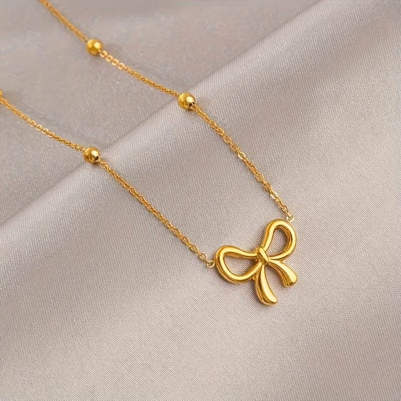 Close-up of gold bow knot charm bracelet with polished chain and accent beads on soft beige satin background - Snap Mart Pakistan