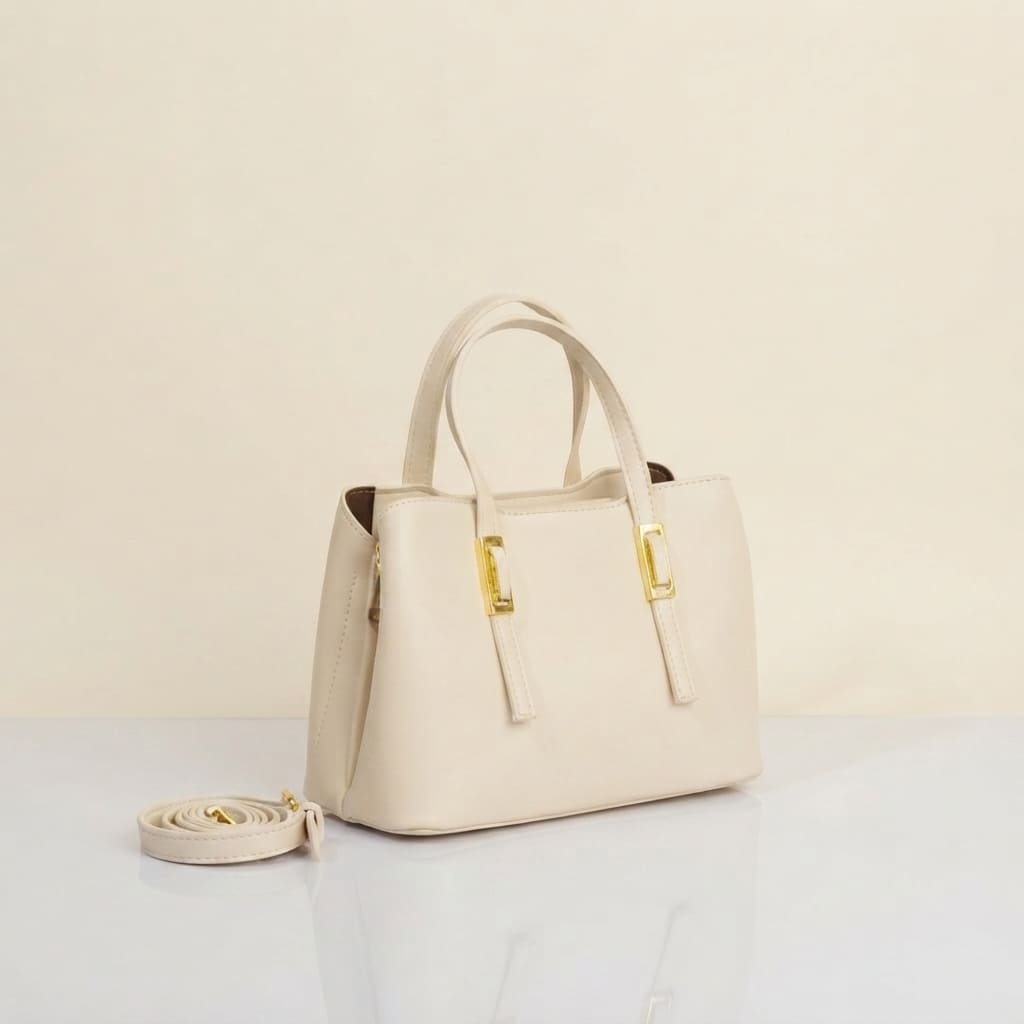 An white leather handbag with gold-tone hardware and a matching detachable shoulder strap, displayed on a light surface against a neutral cream background.