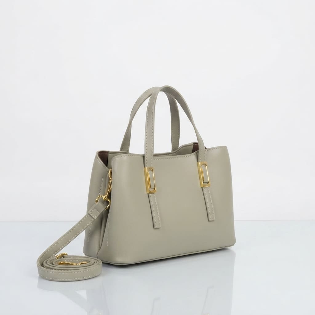 A light gray leather handbag with double top handles, a detachable shoulder strap, and gold-tone hardware, displayed on a clean white background.