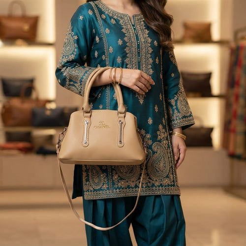 Woman wearing a teal and gold traditional outfit holding the beige handbag by its top handles.