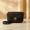 crossbody bag with a gold twist lock and matching fabric strap on a marble surface.