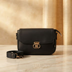 crossbody bag with a gold twist lock and matching fabric strap on a marble surface.