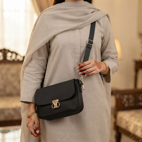 Woman wearing a beige traditional outfit wearing the black crossbody bag over her shoulder.