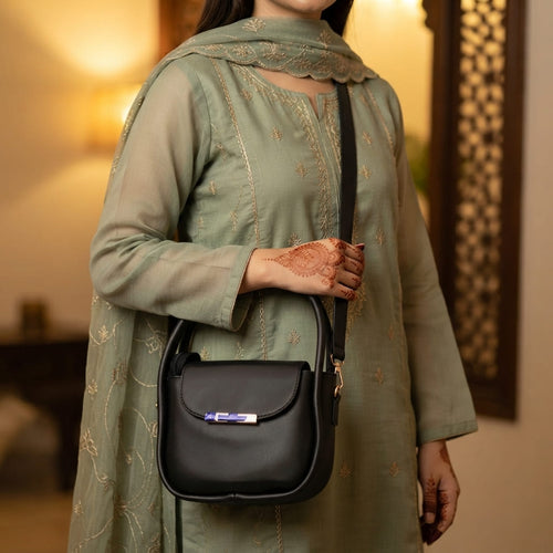 Woman wearing a mint green traditional embroidered outfit holding the black handbag by its top handle.