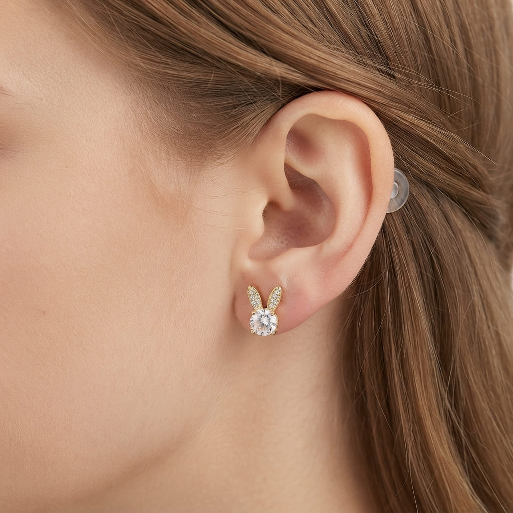 A pair of gold bunny stud earrings with white oval center stones wear by a women - Jewelry Pakistan