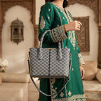 Woman wearing a green traditional outfit holding the grey monogram pattern handbag.