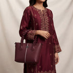 Woman wearing a matching maroon traditional outfit holding the braided-handle maroon handbag.